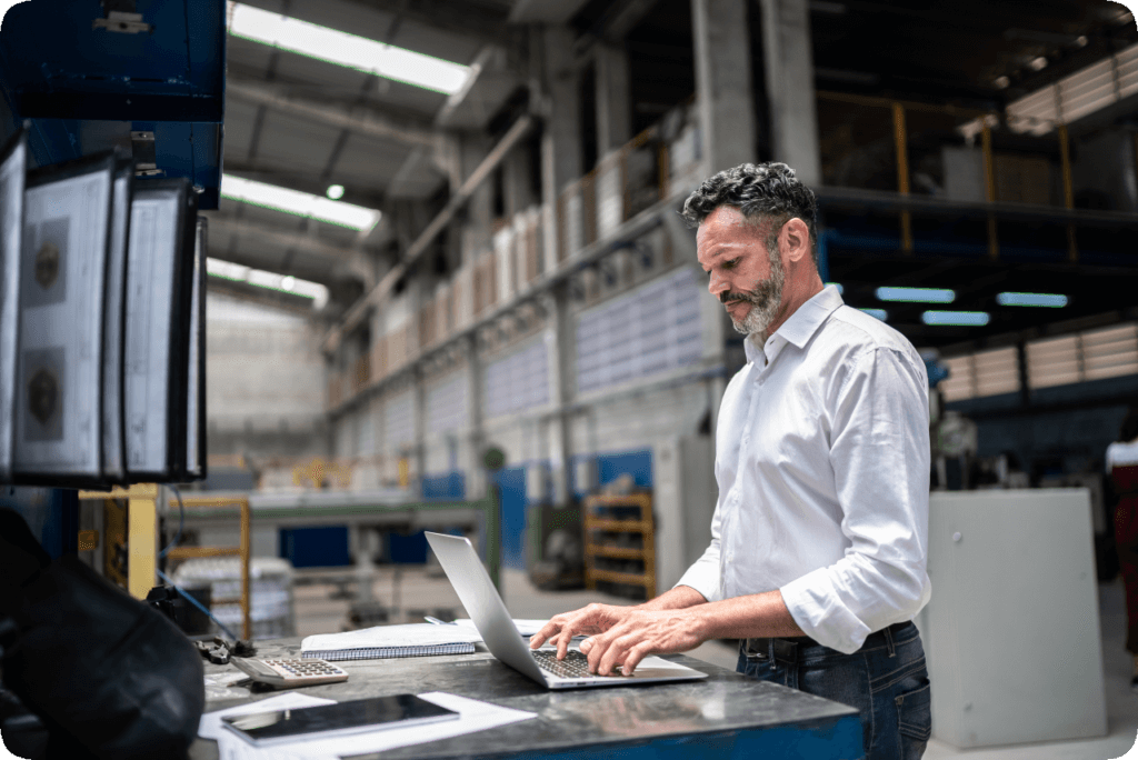 Man standing up in warehouse at laptop